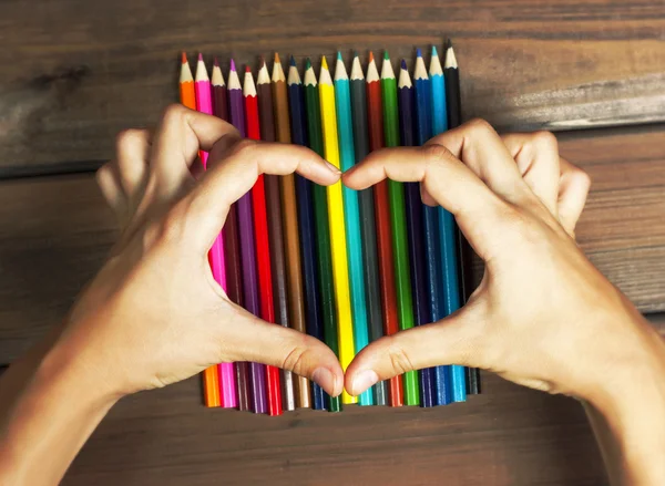 Жіночі руки у формі серця на кольорових олівцях — стокове фото