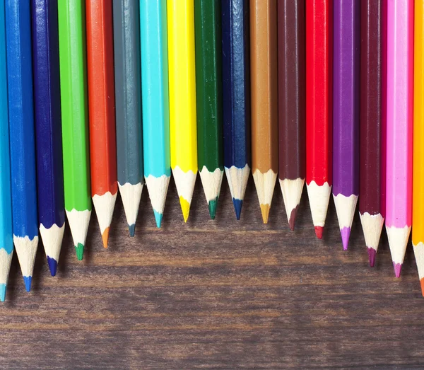 Lápices multicolores sobre un fondo de mesas de madera oscura Imágenes de stock libres de derechos