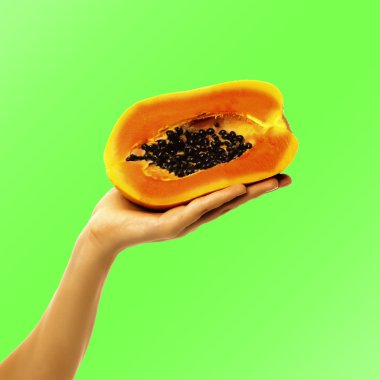 Bir yarım papaya parlak arka planda tutan el