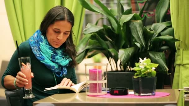 Woman reading book and drinking beverage in restaurant, steadycam shto — Stock Video