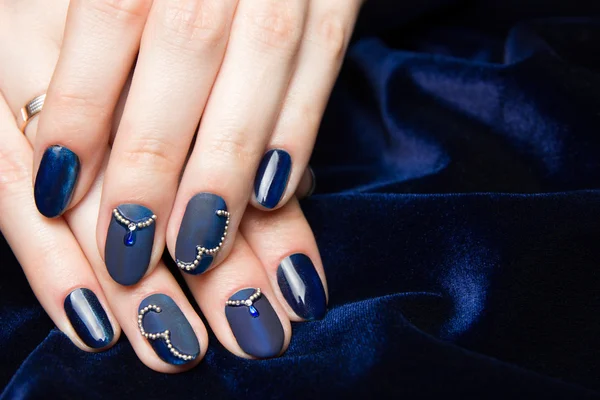 Franse manicure - mooie verzorgde vrouw handen met blauwe manicure met strass op donker blauwe achtergrond — Stockfoto
