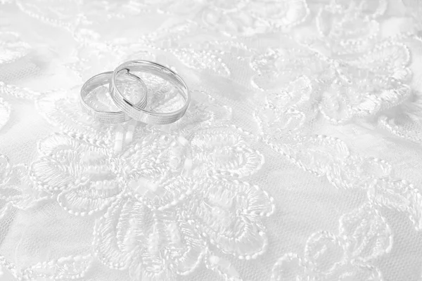 Anillos de boda en la tarjeta de boda, en un vestido de novia blanco — Foto de Stock