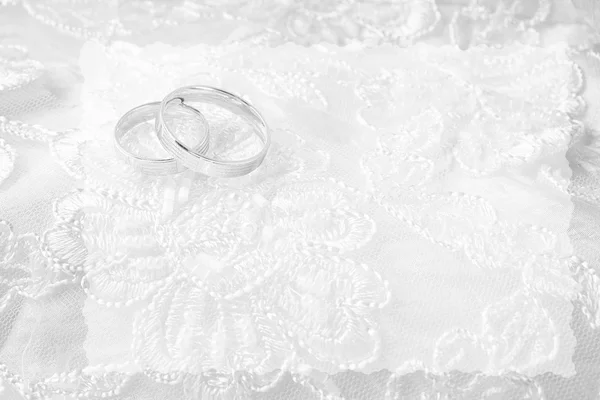 Anillos de boda en la tarjeta de boda, en un vestido de novia blanco — Foto de Stock