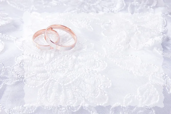 Anelli nuziali sul biglietto da sposa, su un abito da sposa bianco — Foto Stock