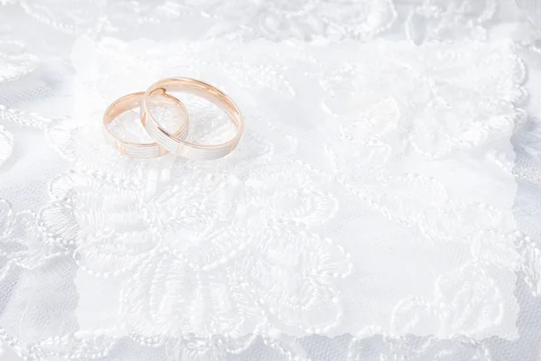 Trauringe auf der Hochzeitskarte, auf einem weißen Hochzeitskleid — Stockfoto