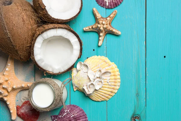 Cocos frescos, aceite de coco en un frasco, conchas y estrellas de mar sobre fondo de madera turquesa natural — Foto de Stock