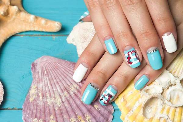 Franse manicure - mooie verzorgde vrouw handen met mariene manicure met strass op achtergrond schelpen en zeesterren — Stockfoto