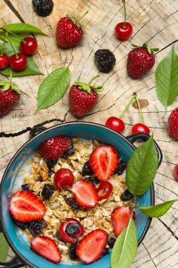 Sağlıklı kahvaltı. Müsli ve meyve taze çilek, kiraz ve Erik ahşap kesme yüzeyi ballı yulaf ezmesi