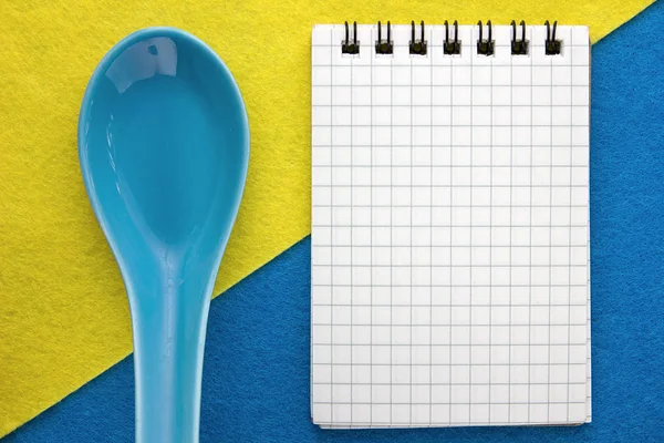 Menu background. Cook book. Recipe notebook on a blue and yellow background. Clay spoon and Notepad.