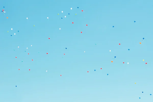 Wielobarwny balony latające w błękitne niebo — Zdjęcie stockowe