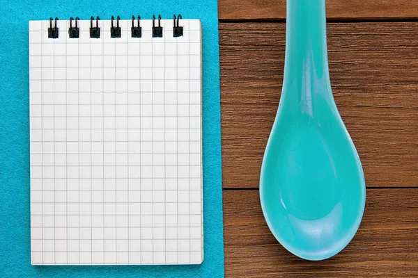 Fondo del menú. Libro de cocina. Libro de notas de la receta sobre fondo azul y textura de madera. Cucharas de arcilla y un bloc de notas . — Foto de Stock