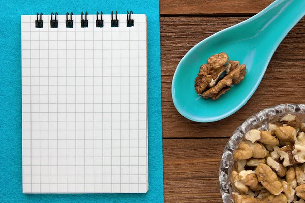 Menu background. Cook book. Recipe notebook with walnuts on a blue background and a wooden board.