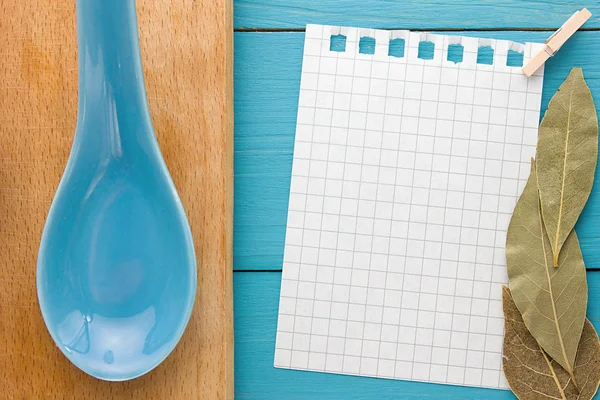 For recording cooking recipes and kitchens. A piece of paper with a pin on turquoise yellow-blue wooden Board and clay spoon — Stock Photo, Image