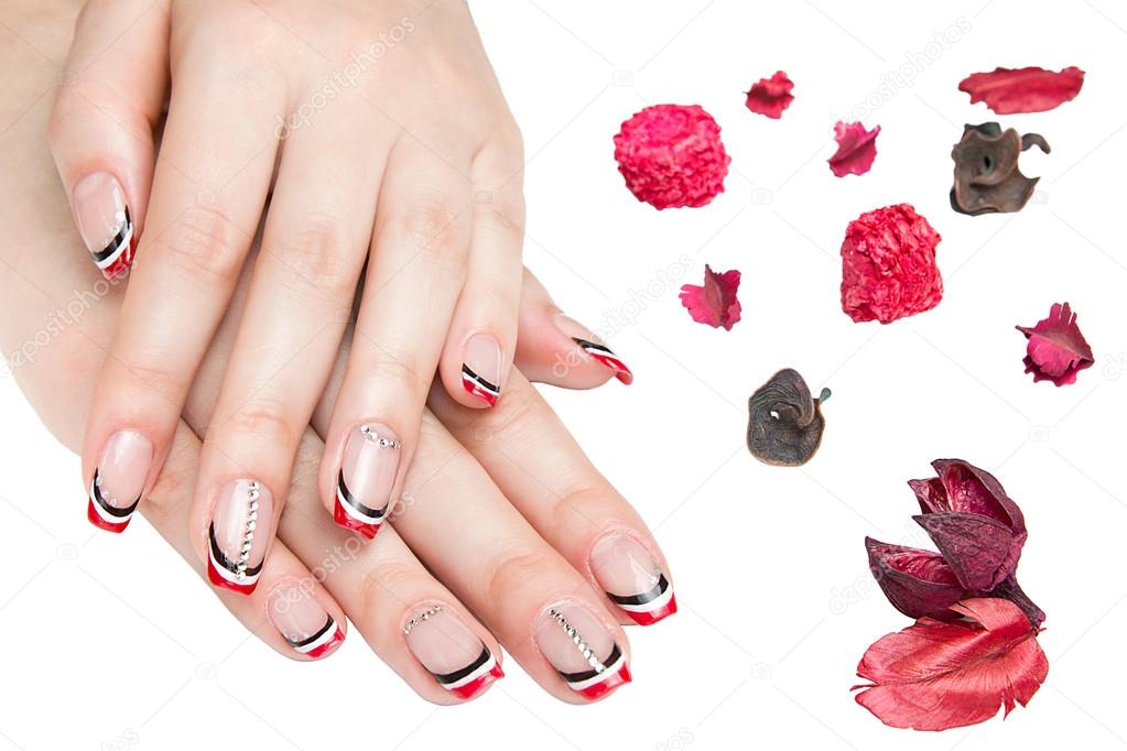 French manicure - beautiful manicured female hands with red black and white manicure with rhinestones isolated on white background
