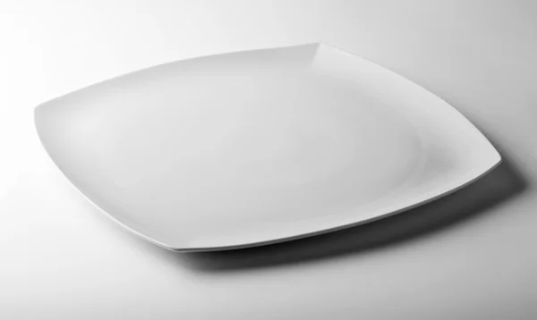 Kwadrat biały talerz na biały stół — Zdjęcie stockowe