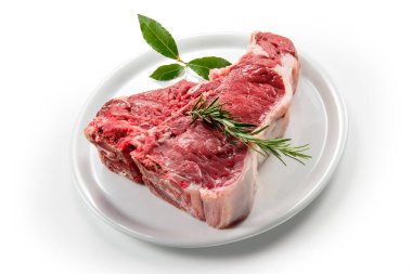 Çiğ biftek, defne yaprağı ve beyaz yuvarlak tabakta biberiye.