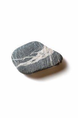 Beyaz arkaplanda gölgesi olan tek bir çakıl taşı