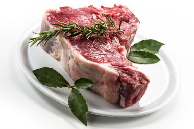 Çiğ biftek, defne yaprağı ve beyaz yuvarlak tabakta biberiye.