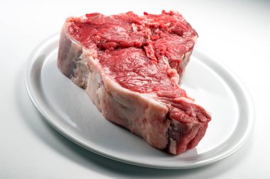 Beyaz arkaplanda çiğ biftek izole edilmiş.
