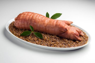 Stuffed pig foot on lentils with bay leaf in oval plate clipart
