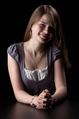 Siyah arka planda uzun kahverengi saçlı genç bir kızın portresi