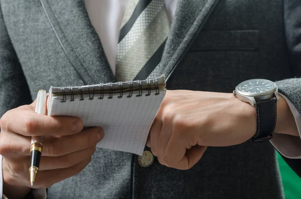 Hombre de negocios comprueba el tiempo registrado en un cuaderno — Foto de Stock