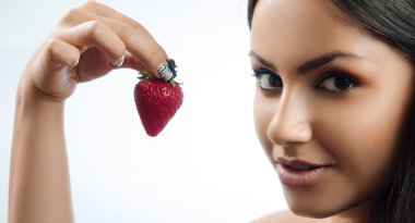 çilek elinde tutan esmer gülümseyen