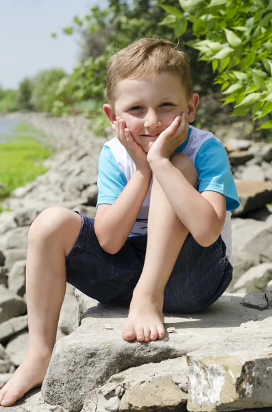 Kleine jongen zit op een rots — Stockfoto