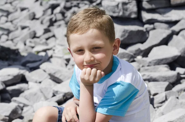 Kleine jongen zit op een rots — Stockfoto