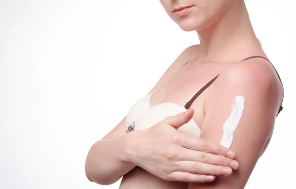 Young woman smears tanned skin cream — Stock Photo, Image