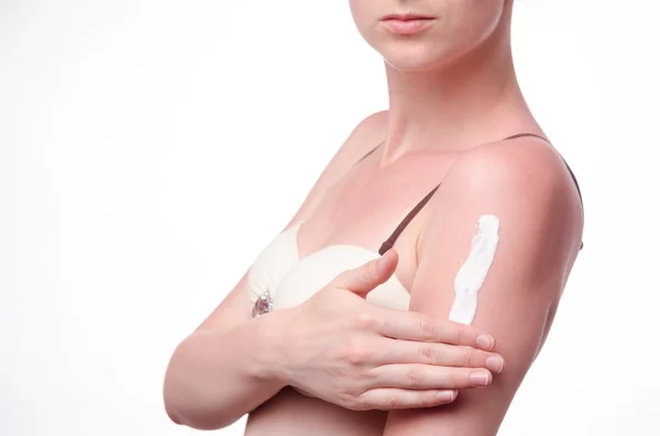 Young woman smears tanned skin cream — Stock Photo, Image