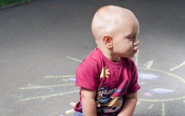 küçük çocuk tebeşir ile kaldırım Pzr çizer. 