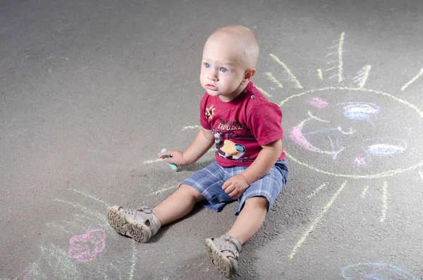 Kleine jongen trekt met krijt op de stoep zon — Stockfoto