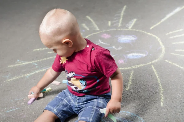 Little boy draws with chalk on the pavement sun — Stock Photo, Image
