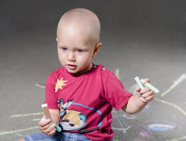 Kleine jongen trekt met krijt op de stoep zon — Stockfoto