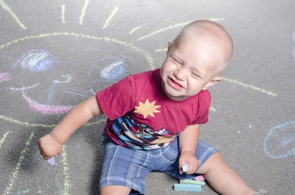 Kleine jongen trekt met krijt op de stoep zon — Stockfoto