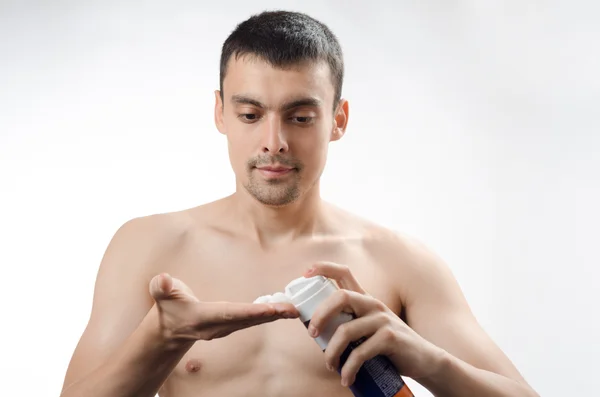 Young man smears shaving gel on your face — Stock Photo, Image