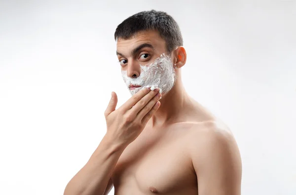 Young man smears shaving gel on your face — Stock Photo, Image