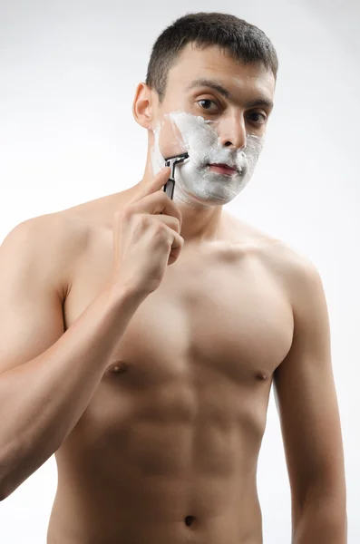 Young man shaving with a razor — Stock Photo, Image