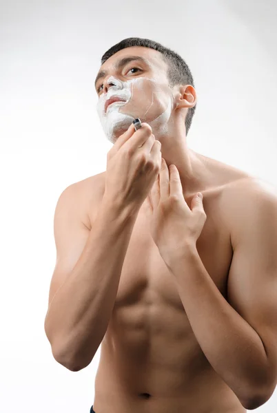 Young man shaving with a razor — Stock Photo, Image