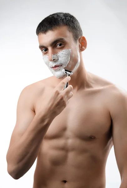 Young man shaving with a razor — Stock Photo, Image