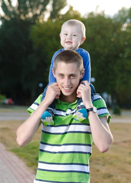 Mladý otec s dítětem na krku procházky v parku — Stock fotografie