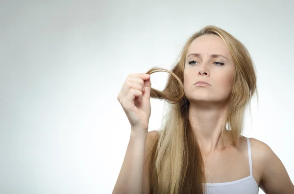 Girl looks at the tips of the cross-section of hair — Stock Photo, Image