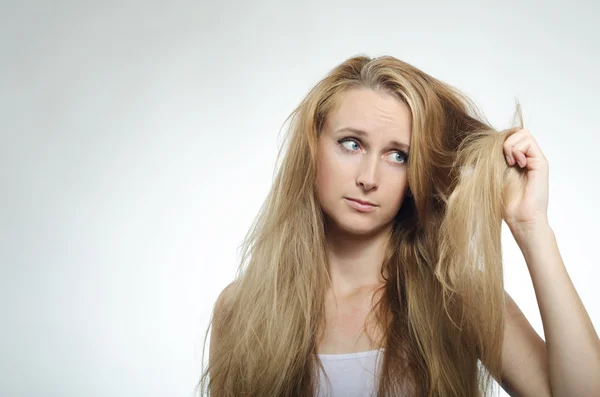 Girl looks at the tips of the cross-section of hair — Stock Photo, Image