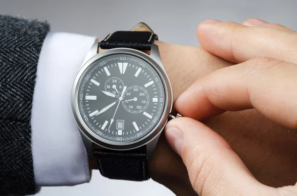Geschäftsmann passt die Uhrzeit an seiner Armbanduhr an — Stockfoto