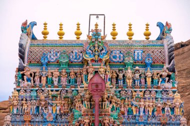 Old south indian temple in close up with full architecture details. Multi colour temple tower in south India surrounded by mountains and rock clipart