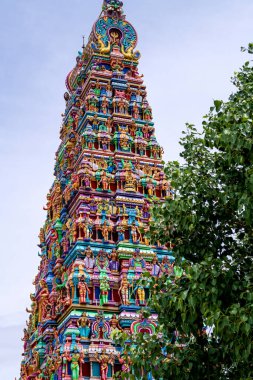 Temple tower in close up with full architecture details. Multi colour temple tower in south India surrounded by the trees clipart