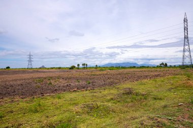 Boş tarım arazisi, sürülmüş tarlalar, verimli, siyah ve kahverengi toprak ekime hazır. Tohum ekmek ve ekmek için tarla hazır. Dağlarla ve palmiyelerle çevrili tarlalar.