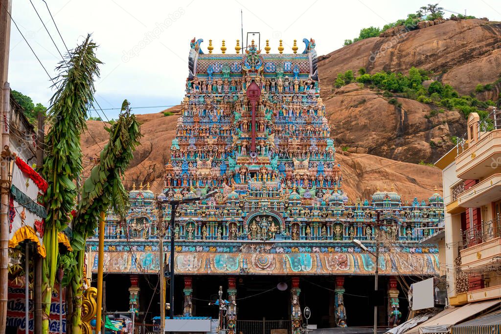Old south indian temple in close up with full architecture details. Multi colour temple tower in south India surrounded by mountains and rock