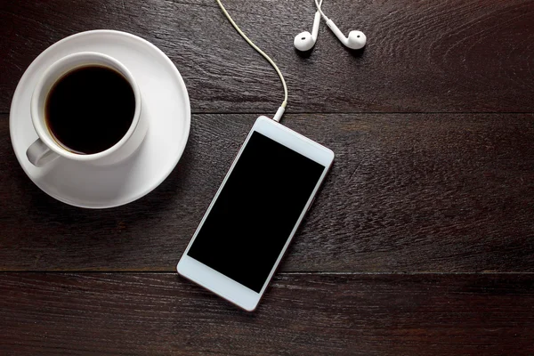 Widok z góry biały smartphone, Czarna kawa, słuchawki na stół z drewna. — Zdjęcie stockowe